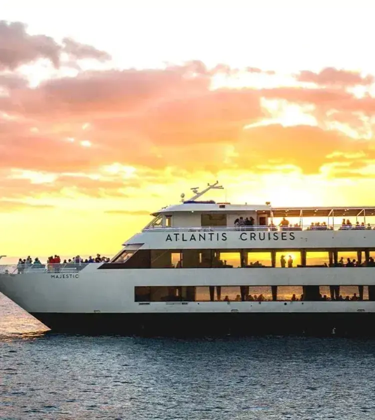 large cruise ship on ocean at sunset with orange and pink sky